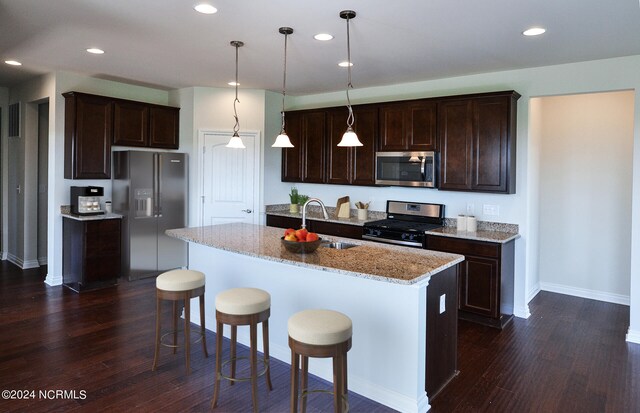 kitchen featuring appliances with stainless steel finishes, dark hardwood / wood-style floors, a center island with sink, and sink