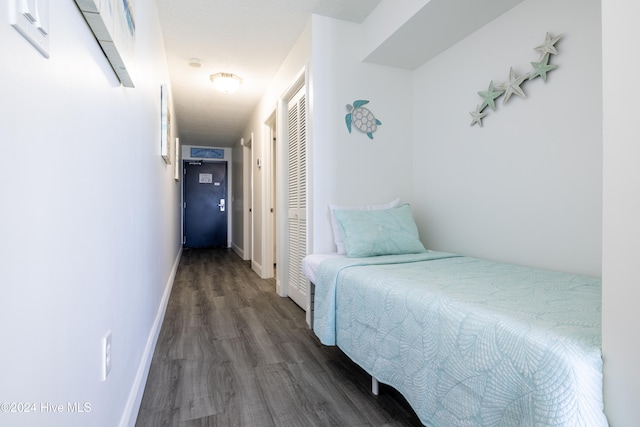 bedroom with dark wood-style floors, a closet, and baseboards