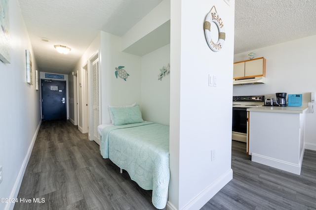 hall featuring a textured ceiling, dark wood finished floors, and baseboards