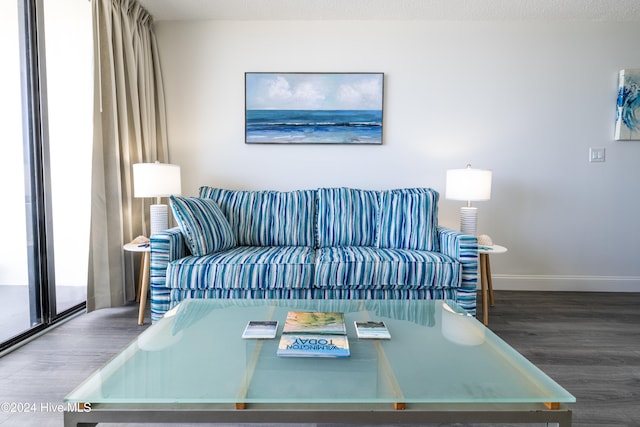 living room with a textured ceiling, baseboards, and wood finished floors