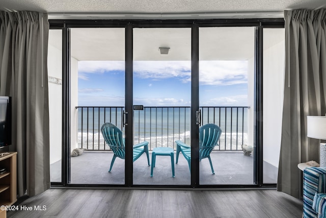 entryway featuring expansive windows, a textured ceiling, a water view, and wood finished floors