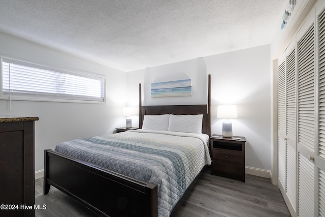 bedroom featuring a closet, a textured ceiling, baseboards, and wood finished floors