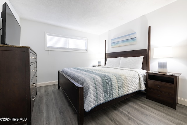 bedroom with a textured ceiling, wood finished floors, and baseboards