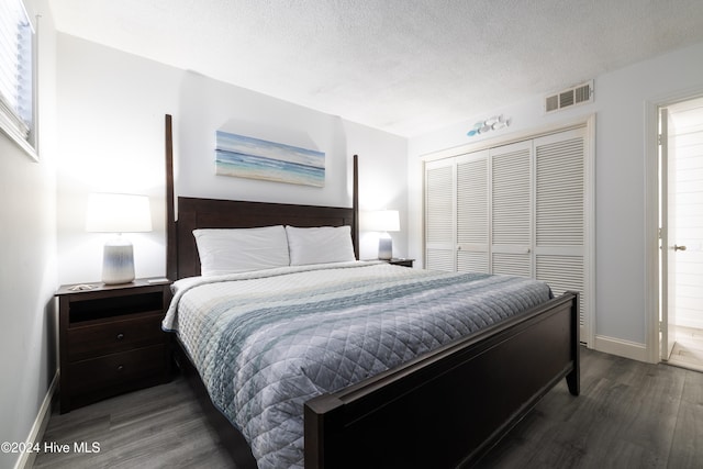 bedroom with baseboards, visible vents, wood finished floors, a textured ceiling, and a closet