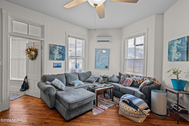 living area with a wealth of natural light, wood-type flooring, a ceiling fan, and a wall unit AC