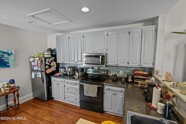 kitchen with dark countertops, wood finished floors, backsplash, and stainless steel appliances