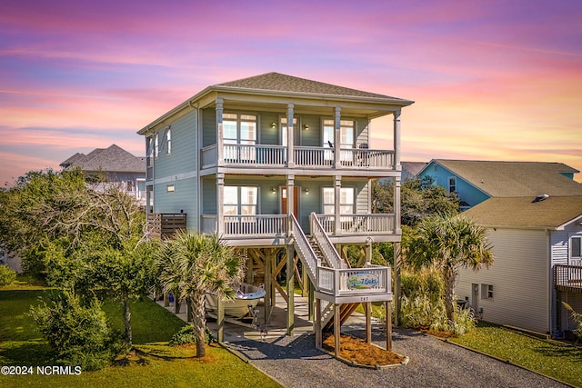 coastal home with a balcony, a yard, and covered porch