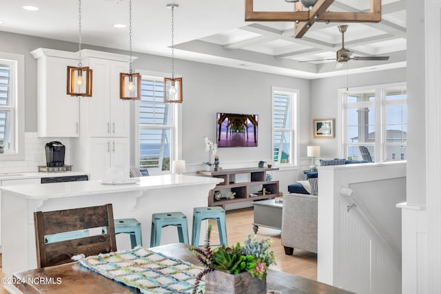 kitchen with plenty of natural light, a kitchen breakfast bar, coffered ceiling, and white cabinetry