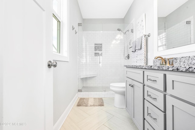 bathroom featuring tile patterned flooring, a tile shower, vanity, and toilet