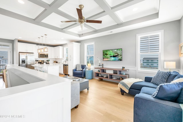 living room featuring ceiling fan, beamed ceiling, coffered ceiling, and light hardwood / wood-style floors