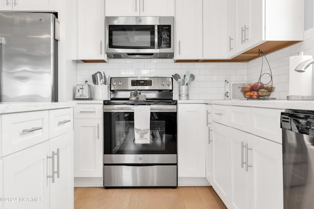 kitchen with backsplash, appliances with stainless steel finishes, light wood-type flooring, and white cabinetry