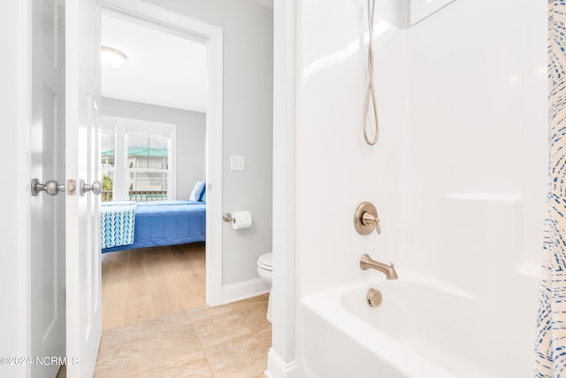 bathroom featuring shower / bath combination with curtain, hardwood / wood-style floors, and toilet