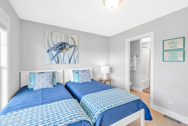 bedroom with light hardwood / wood-style floors and connected bathroom