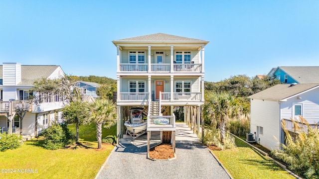 coastal home with a front yard, a balcony, covered porch, and a carport