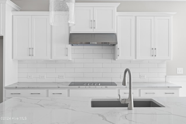 kitchen featuring white cabinetry, light stone countertops, wall chimney range hood, and black electric cooktop