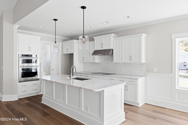 kitchen featuring hanging light fixtures, double oven, an island with sink, white cabinets, and hardwood / wood-style flooring