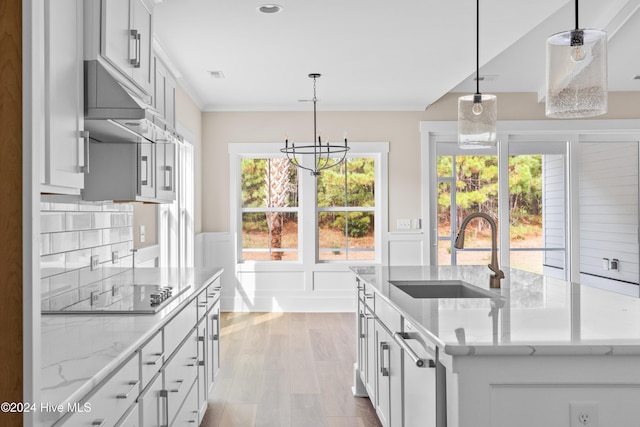 kitchen featuring a kitchen island with sink, sink, pendant lighting, and black electric stovetop