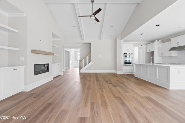 unfurnished living room with ceiling fan, sink, high vaulted ceiling, and light hardwood / wood-style floors