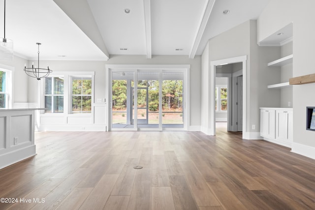 unfurnished living room featuring a healthy amount of sunlight, lofted ceiling, and hardwood / wood-style flooring