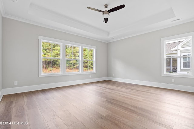 unfurnished room with a raised ceiling, ceiling fan, light hardwood / wood-style floors, and ornamental molding