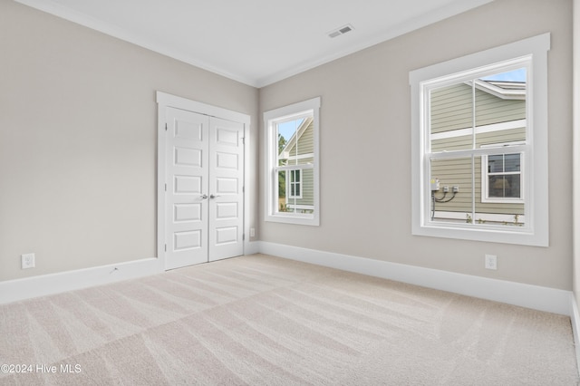 unfurnished bedroom with ornamental molding, light carpet, and a closet