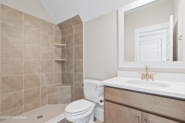 bathroom with vanity, toilet, lofted ceiling, and a tile shower