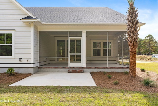 rear view of property featuring a yard, a patio, and a sunroom