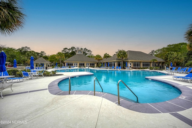 pool at dusk featuring a patio