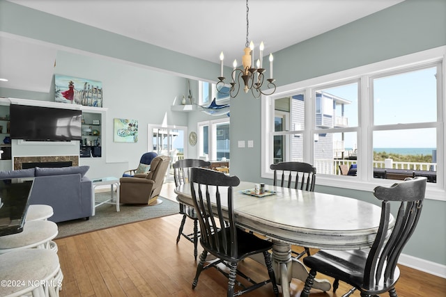 dining space with a fireplace, a notable chandelier, baseboards, and wood finished floors