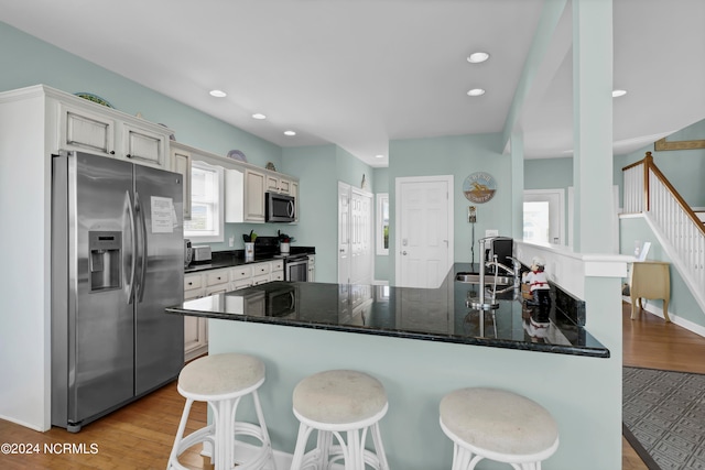 kitchen with appliances with stainless steel finishes, white cabinetry, a wealth of natural light, and light hardwood / wood-style floors