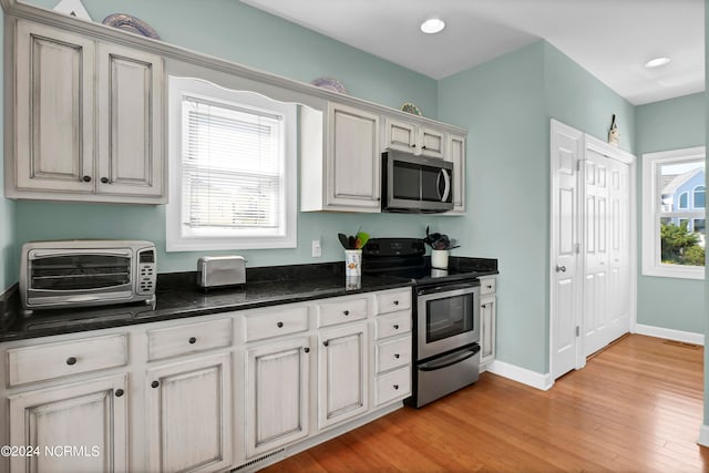 kitchen with appliances with stainless steel finishes, a healthy amount of sunlight, and light hardwood / wood-style flooring