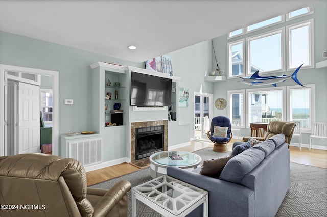 living room with a fireplace, wood finished floors, visible vents, and baseboards