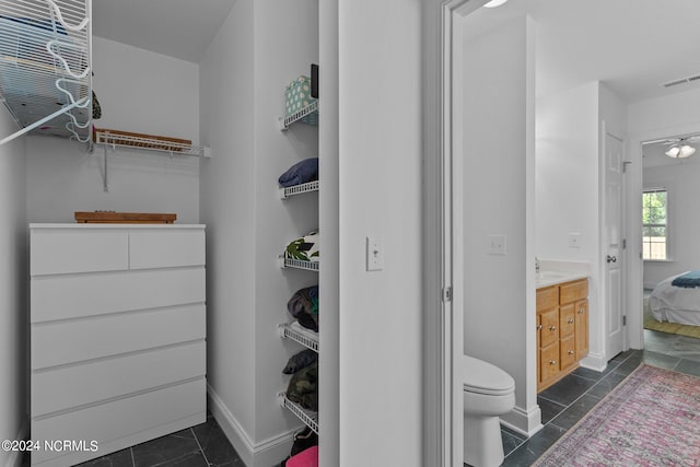 spacious closet with ceiling fan and dark tile patterned floors