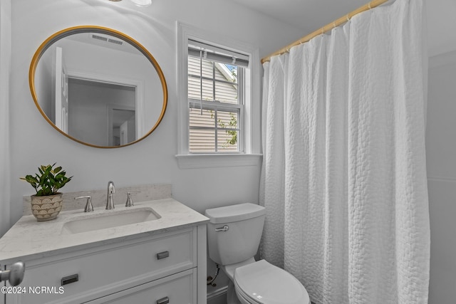 bathroom with walk in shower, vanity, and toilet