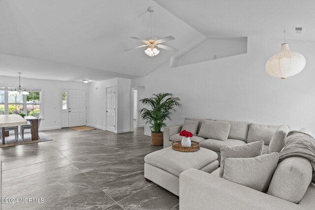 living room featuring ceiling fan with notable chandelier and vaulted ceiling