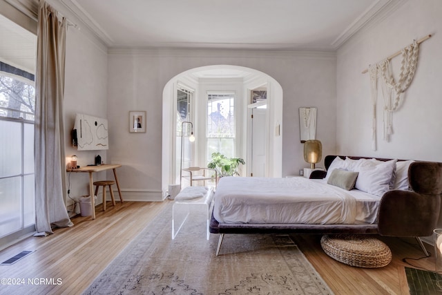 bedroom with multiple windows, light hardwood / wood-style floors, and crown molding