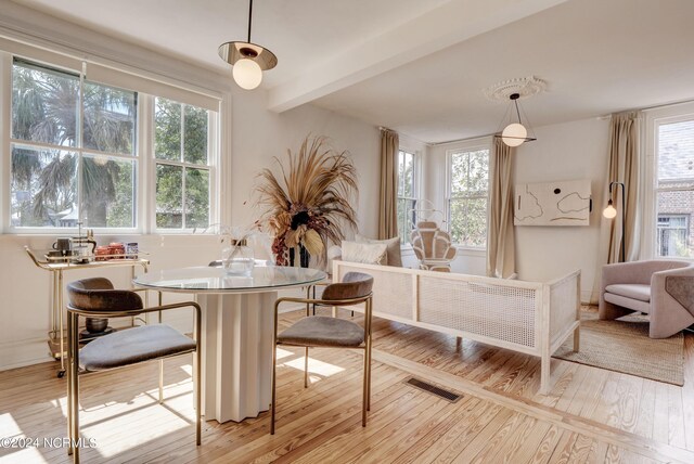 dining area with beam ceiling and light hardwood / wood-style floors