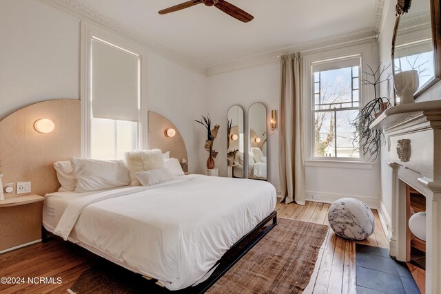 bedroom with hardwood / wood-style floors, ceiling fan, and crown molding