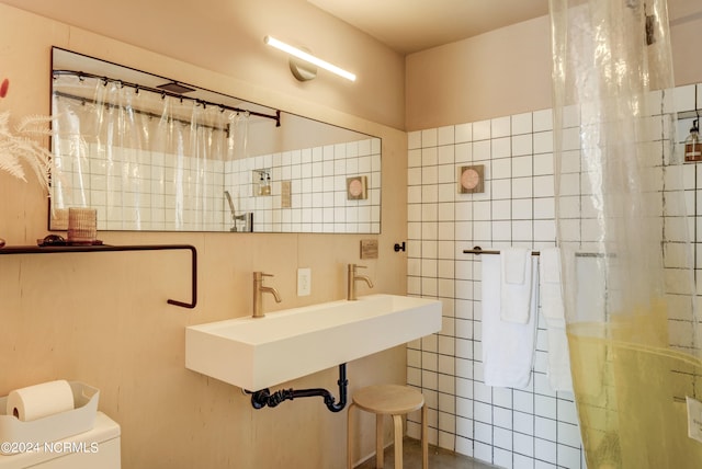 bathroom with tile walls, toilet, a shower with curtain, and sink