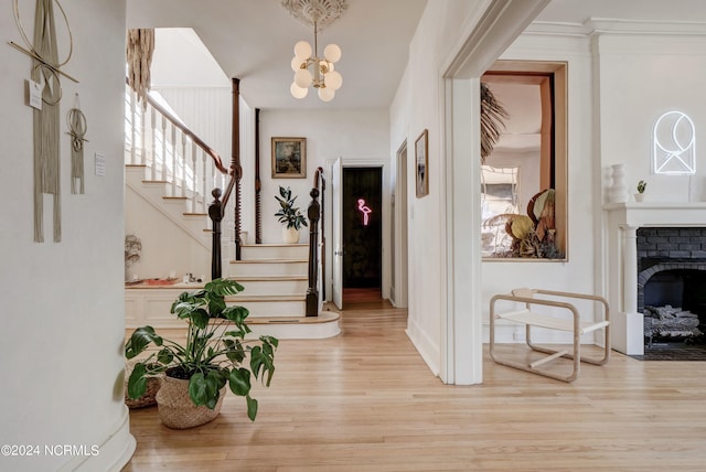 foyer entrance featuring a wealth of natural light, light hardwood / wood-style flooring, a chandelier, and a fireplace