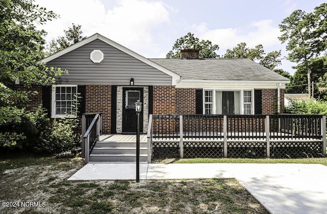 view of front of house with a chimney, a deck, and brick siding