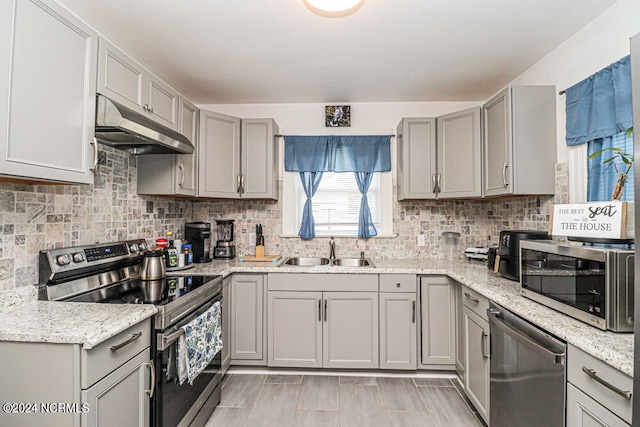 kitchen with gray cabinetry, stainless steel appliances, sink, and decorative backsplash