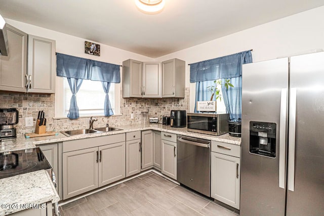 kitchen with gray cabinetry, appliances with stainless steel finishes, backsplash, and sink