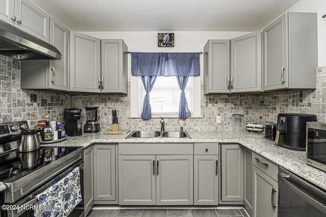 kitchen with under cabinet range hood, appliances with stainless steel finishes, a sink, and gray cabinetry