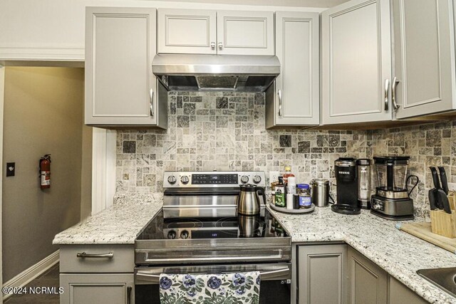 kitchen with under cabinet range hood, tasteful backsplash, stainless steel electric range, and gray cabinetry