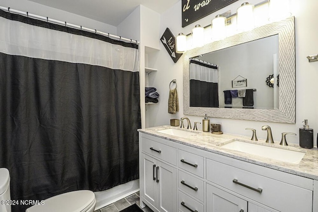 full bathroom featuring double vanity, a sink, and toilet