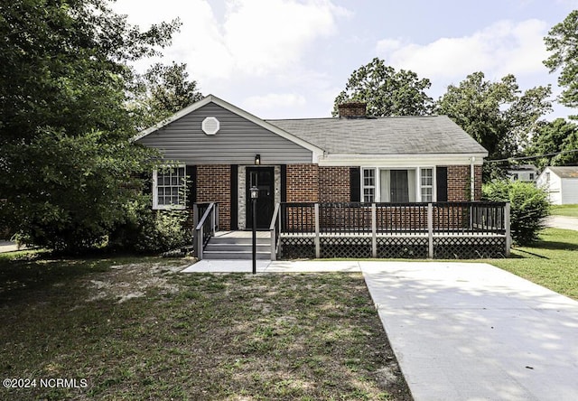 view of front of house featuring a deck, a front yard, brick siding, and a chimney