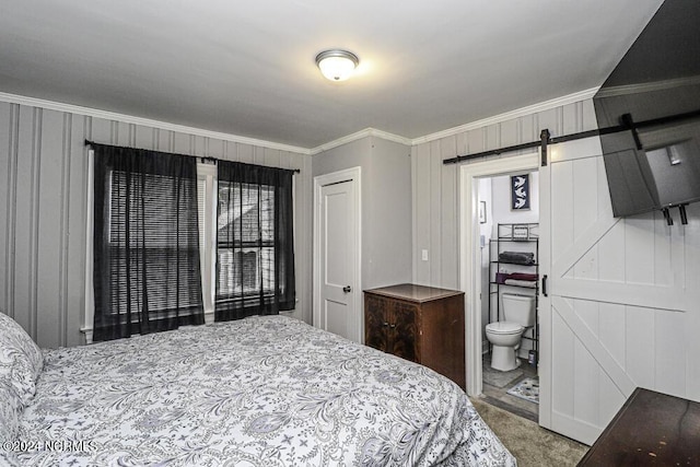 bedroom featuring a barn door, crown molding, and ensuite bathroom