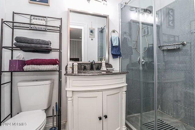 bathroom with a shower with door, vanity, and toilet