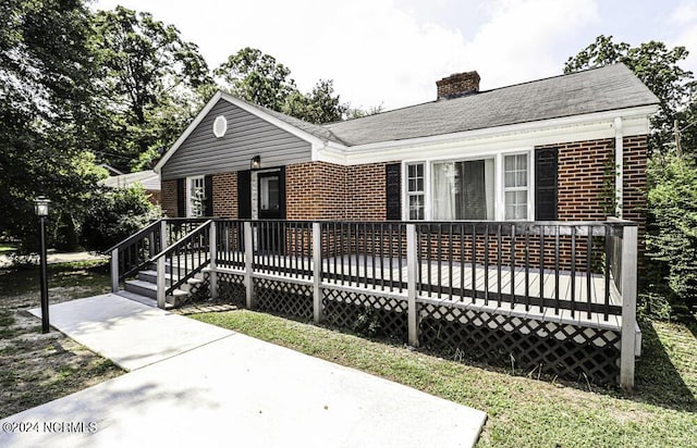 view of front of house with a shingled roof, a chimney, and brick siding